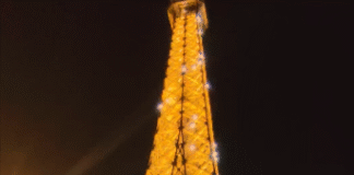 The Eiffel Tower sparkles at night in Paris with its brilliant lights and reflections in the dark sky.